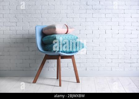 Different pillows on chair in room Stock Photo