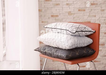 Different pillows on chair in room Stock Photo