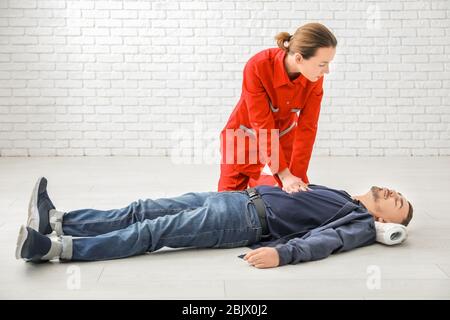 Young woman giving first aid to unconscious man on floor, indoors Stock Photo