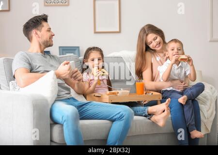 Happy family having breakfast on sofa at home Stock Photo