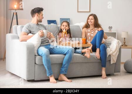 Happy family having breakfast on sofa at home Stock Photo