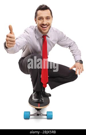 Young businessman kneeling and riding a skateboard and showing thumbs up isolated on white background Stock Photo