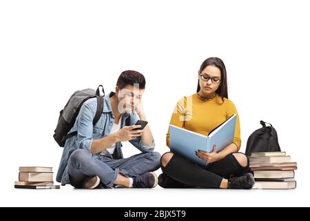 Female student reading a book and bored male student looking at his mobile phone isolated on white background Stock Photo