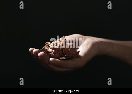 Poor woman holding piece of bread on dark background Stock Photo