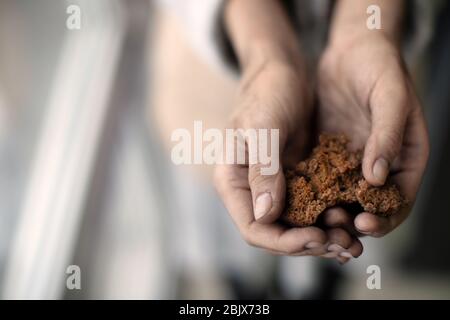Poor woman holding bread on blurred background Stock Photo