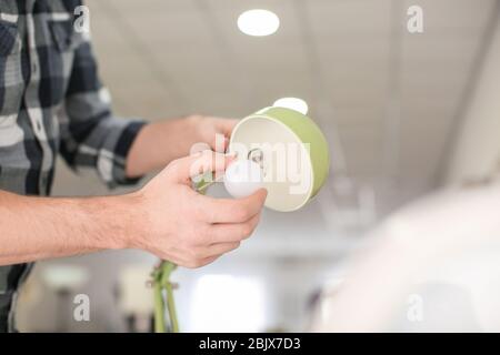Man changing light bulb in lamp at home Stock Photo