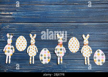 Easter bunnies and eggs made from patterned paper on wooden background Stock Photo