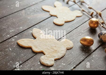 Raw bunny shaped cookies and eggs on wooden background. Easter celebration Stock Photo