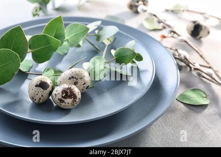 Eucalyptus twigs and quail eggs on plate as decor for Easter table setting Stock Photo
