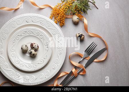 Beautiful festive Easter table setting with mimosa and quail eggs Stock Photo