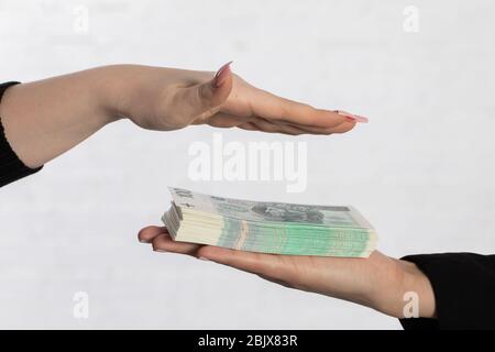 One hand is held over a bundle of paper banknotes making a kind of roof over them. Stock Photo