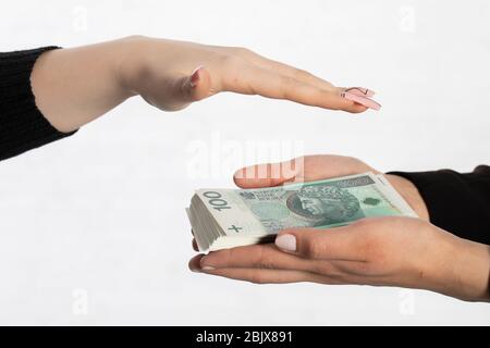 One hand is held over a bundle of paper banknotes making a kind of roof over them. Stock Photo