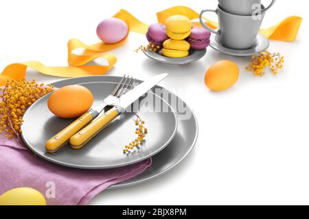 Beautiful festive Easter table setting with mimosa and painted eggs on white background Stock Photo
