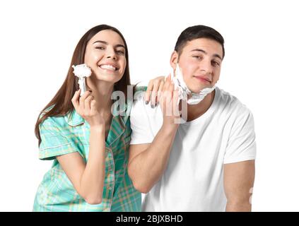 Young woman having fun while her boyfriend shaving on light background Stock Photo