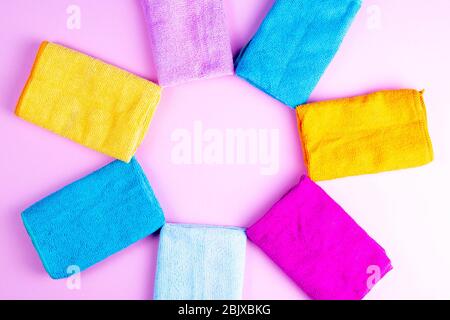 Multi-colored towels laid out in the form of the sun on a pink background. Pink, beige, yellow, orange and blue towels. Place for writing. House order Stock Photo