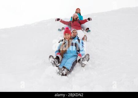 Group of happy friends sliding down the snowy hill. Winter vacation Stock Photo