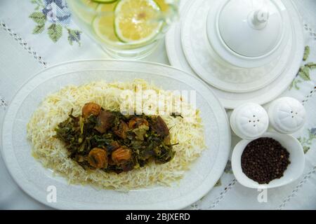 A bowl of white ceramic salt and pepper. Shah pilaf. Khan pilaf in a pita. Black pepper in a white ceramic pot . There is meat and plum chestnuts on Stock Photo