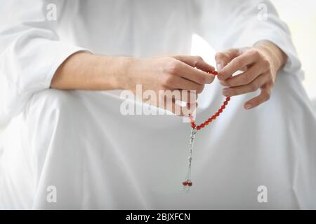 Young Muslim man holding beads, closeup Stock Photo