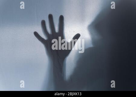 A mans hand shot through a semi transparent material. Creating a spooky  textured, blurred, still life. Stock Photo