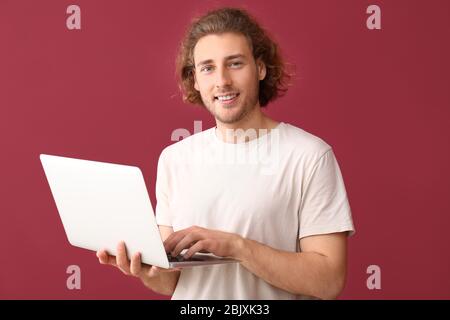 Male programmer with laptop on color background Stock Photo