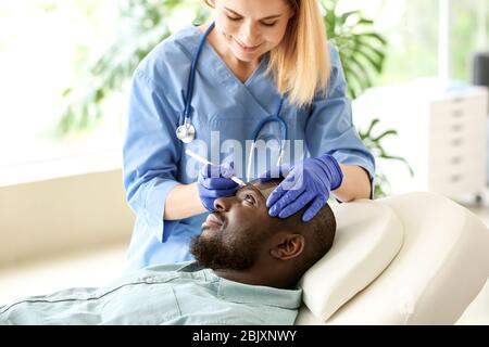 Plastic surgeon applying marks on patient's face in clinic Stock Photo