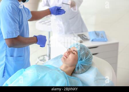 Plastic surgeon preparing woman for operation in clinic Stock Photo
