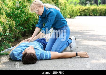 Woman giving CPR to unconscious man outdoors Stock Photo