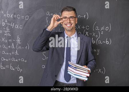 Handsome math teacher near blackboard in classroom Stock Photo