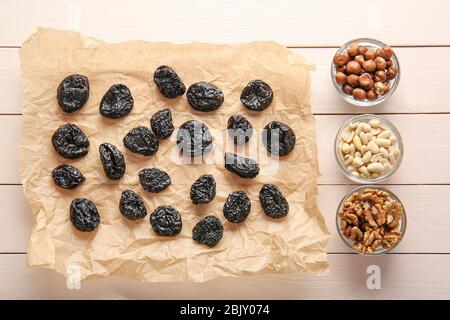Tasty prunes with nuts on white wooden background Stock Photo