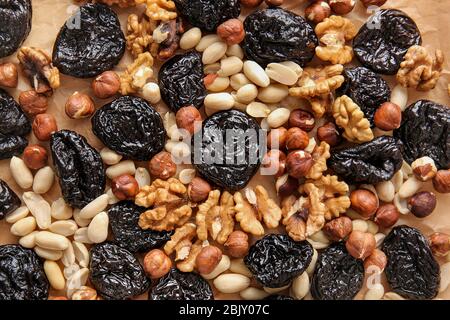 Tasty prunes with nuts on parchment, top view Stock Photo