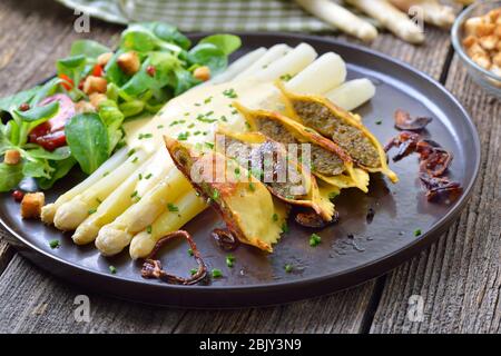 White asparagus with fried stuffed Swabian-style meat ravioli served with corn salad with croutons Stock Photo