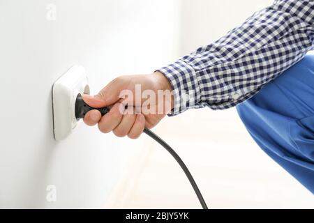 Electrician inserting plug in socket, closeup Stock Photo
