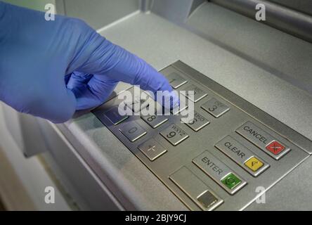 Gloved hand pushing button of cash machine Stock Photo