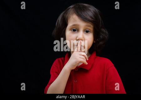 Cute  kid put index finger over lips for  quiet gesture Stock Photo