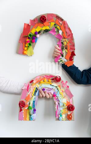 Kids hands holding their rainbow arts and crafts Stock Photo