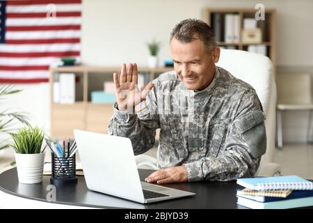 Mature male soldier using laptop in headquarters building for ...