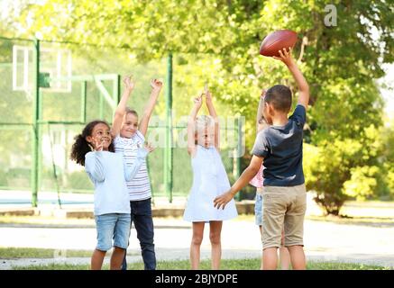 Cute little children playing with rugby ball in park Stock Photo