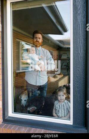 Father with children (2-5 months, 2-3) looking through window Stock Photo