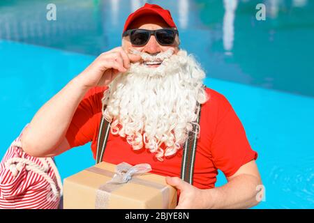 Santa Claus with gifts near swimming pool at resort Stock Photo