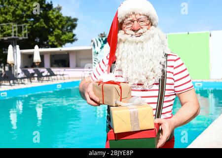 Santa Claus with gifts near swimming pool at resort Stock Photo