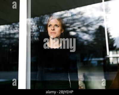 Woman looking through window Stock Photo
