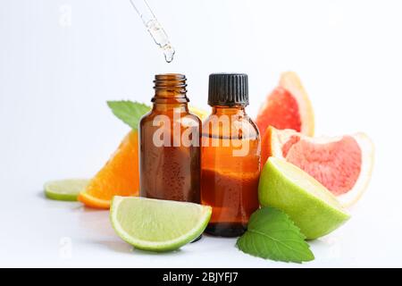 Citrus essential oil dripping from pipette into bottle on white background Stock Photo