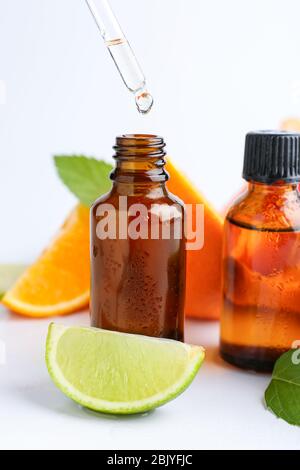 Citrus essential oil dripping from pipette into bottle on white background Stock Photo