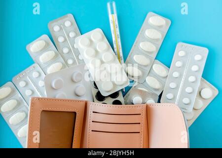 Empty wallet with white tablets of pills on  blue background Stock Photo