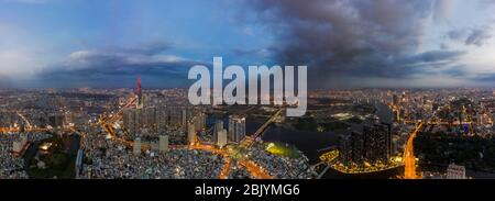 Evening aerial panorama of Saigon, Vietnam featuring new high rise developments on the river front, city center and infrastructure with city lights on Stock Photo