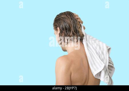 Handsome young man after washing hair against color  background Stock Photo