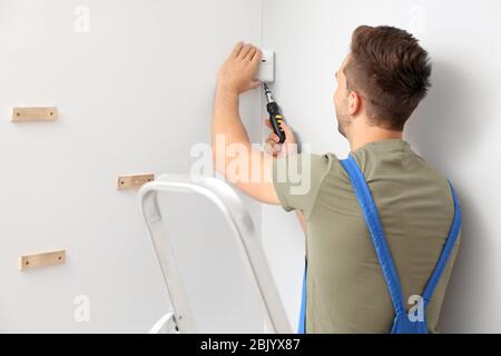 Electrician installing alarm system indoors Stock Photo