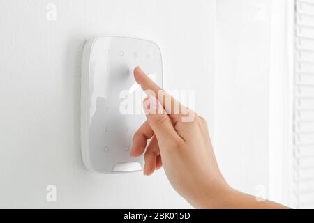 Woman entering code on panel of modern security system Stock Photo