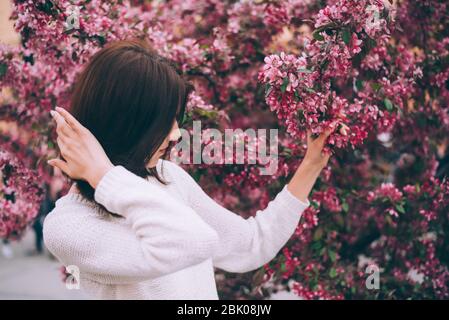 Girl holds a branch of blossoming spring flowers in hands. Close up of beautiful female hands holding a branch of blossoming fruit tree. Delicate spri Stock Photo