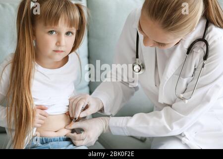 Doctor giving diabetic girl insulin injection at home Stock Photo